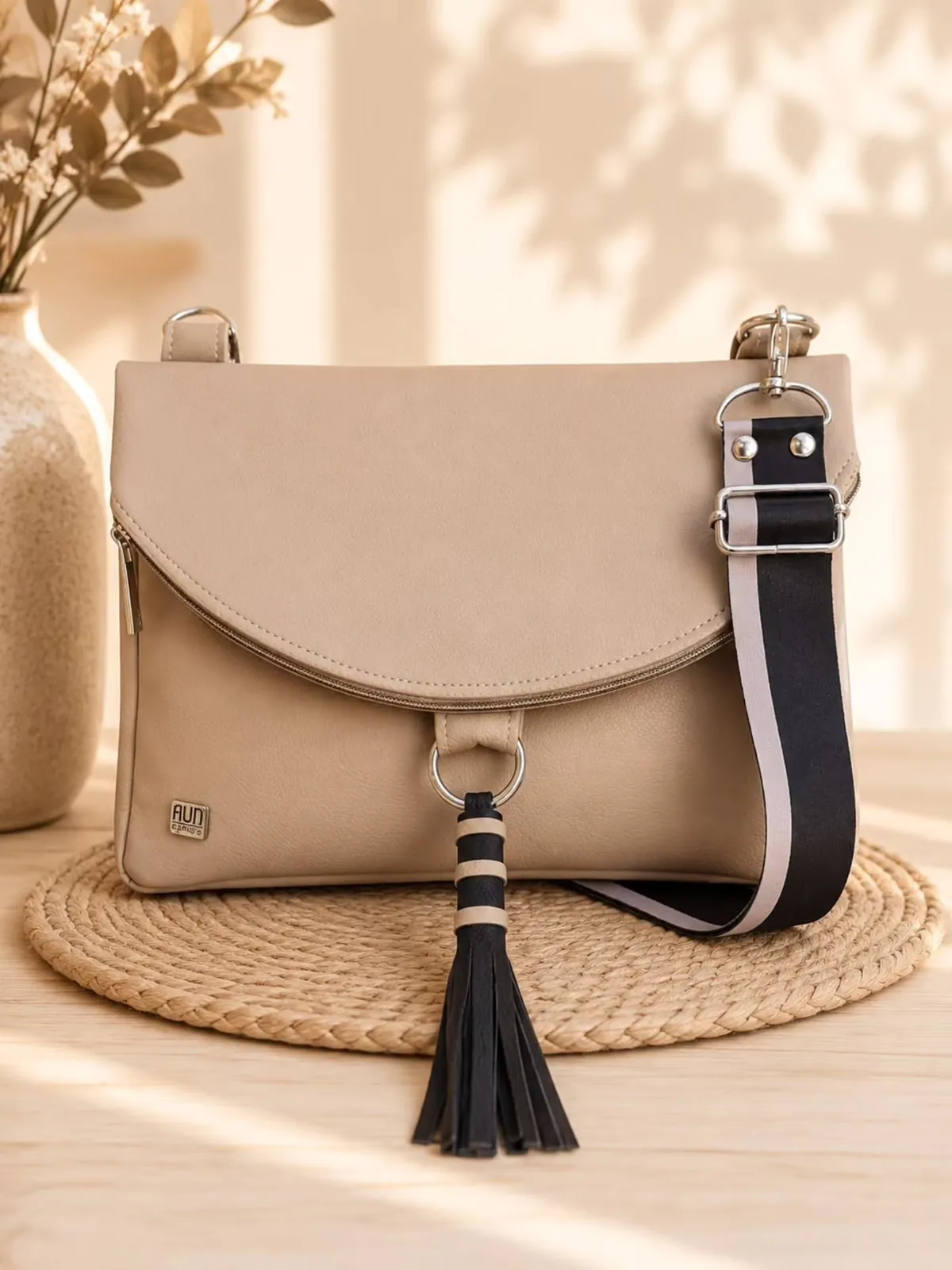 Cartera Aún beige con borla negra y correa rayada