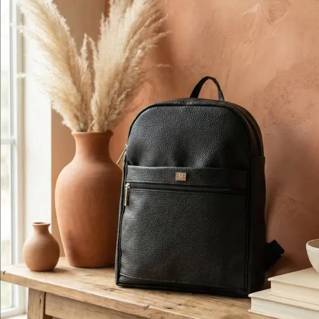 Mochila negra junto a un jarrón de terracota